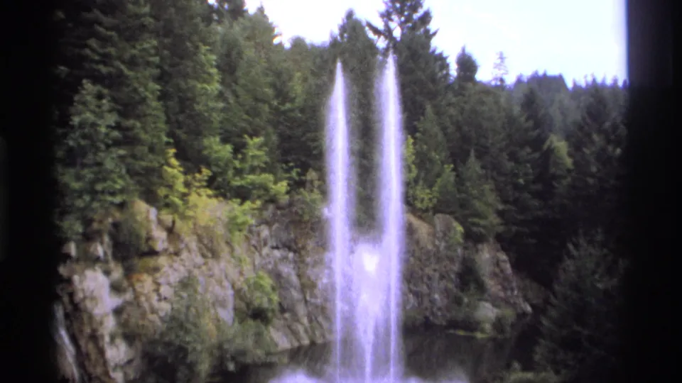 1974 Vancouver-area 8mm frame with high water spray, mist, rock faces, and dense conifers in soft vintage color.