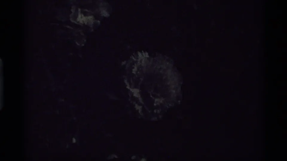 Very dark 8mm frame from the Vancouver ferry clip, with only faint surface shapes and the film frame edge visible.