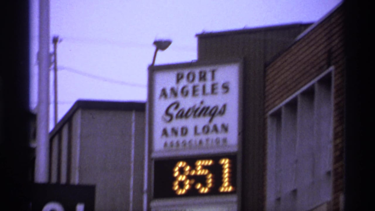 Closer repeat view of the savings and loan sign, time display, and building facade.