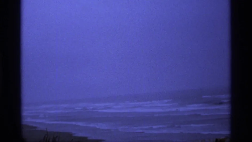 Blue-shifted 8mm view of distant ocean surf near Vancouver, framed by dark gate edges and a soft horizon.