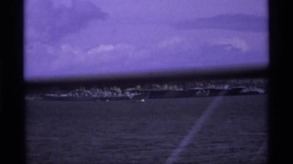 1974 Vancouver travel footage shifts to a waterfront or harbor view with distant shoreline under a purple-tinted sky.