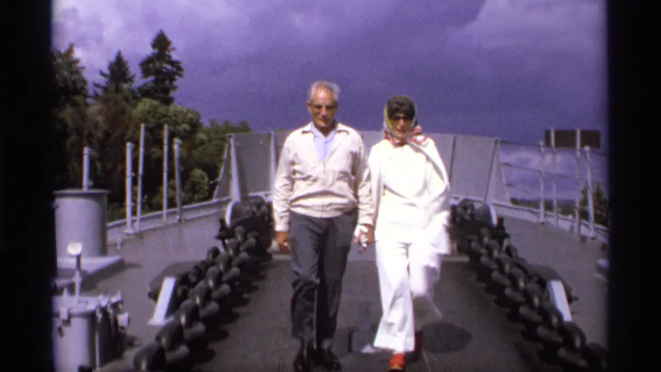 In Vancouver in 1974, two adult visitors walk toward the camera on the USS Missouri deck under a cloudy sky.