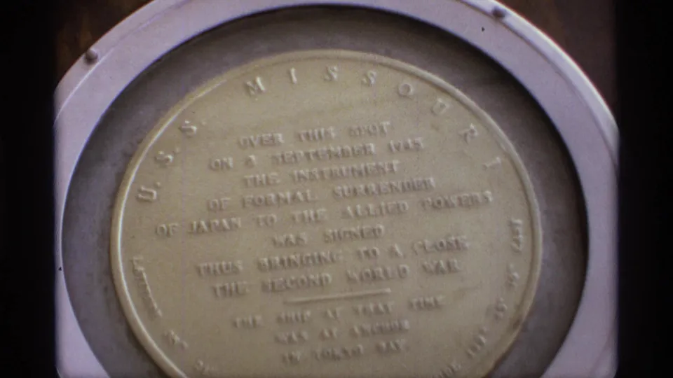 A final close frame centers the USS Missouri surrender plaque, with its inscription visible through soft home-movie focus.