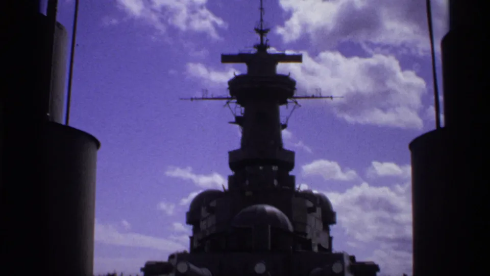 Low-angle 1974 Vancouver home-movie view of the USS Missouri superstructure framed between dark foreground ship elements.