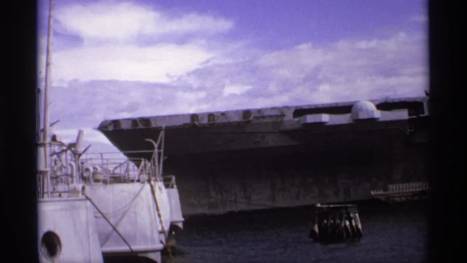 1974 Vancouver harbor shot showing the USS Missouri's broad gray hull at dock with foreground railings and water.