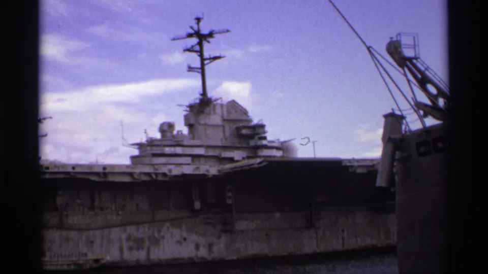 1974 Vancouver 8mm frame with a closer view of the naval vessel's island, mast, weathered hull, and crane rigging nearby.