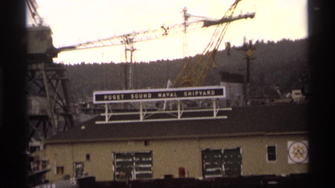 Shipyard cranes behind a building with a Puget Sound Naval Shipyard sign.