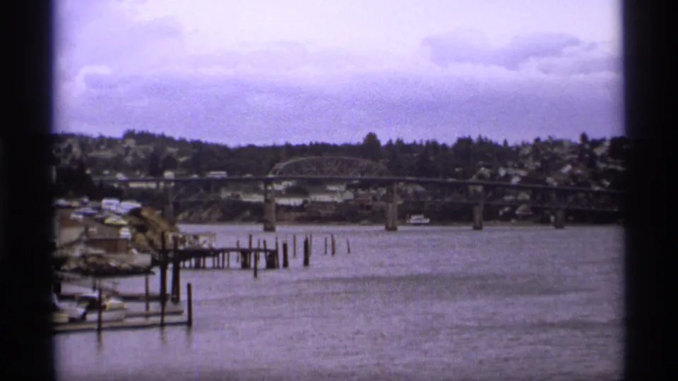 1974 Vancouver river scene showing a bridge, moored boats, waterfront pilings, and houses across the water.