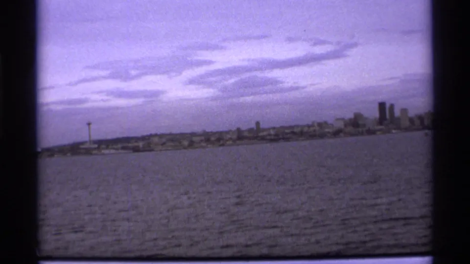 1974 8mm waterfront view of Vancouver, with open water in front and a needle-like tower visible left of the skyline.