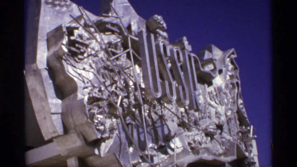 Close view of metallic USSR lettering and relief decoration, filmed outdoors on 8mm with a deep blue sky behind it.