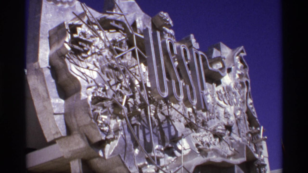 Metallic USSR sign and sculptural relief against a deep blue sky.