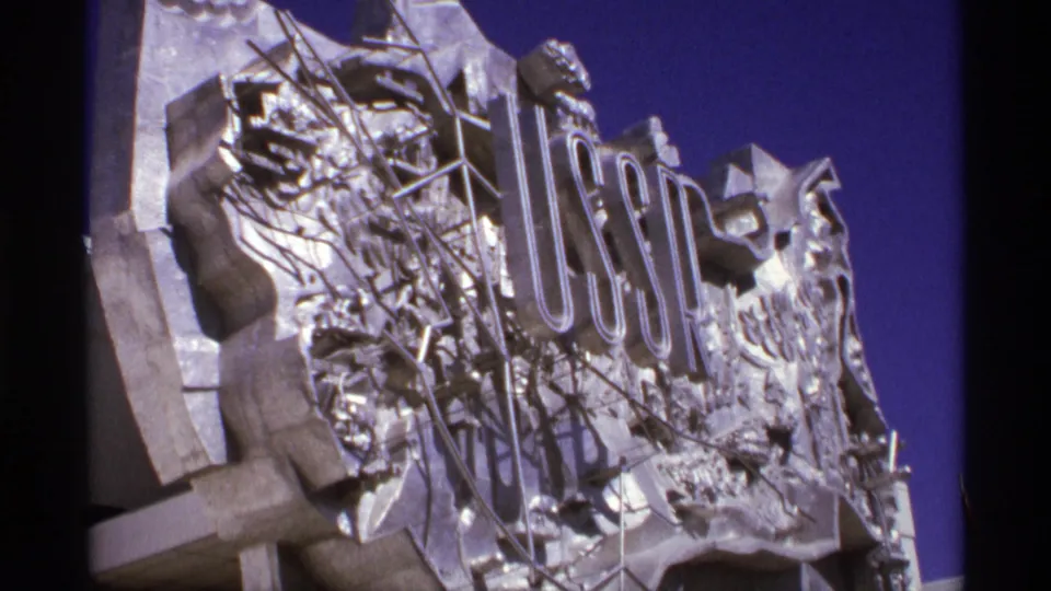 1974 World's Fair footage showing a metallic USSR pavilion sign with sculptural relief under a saturated blue sky.