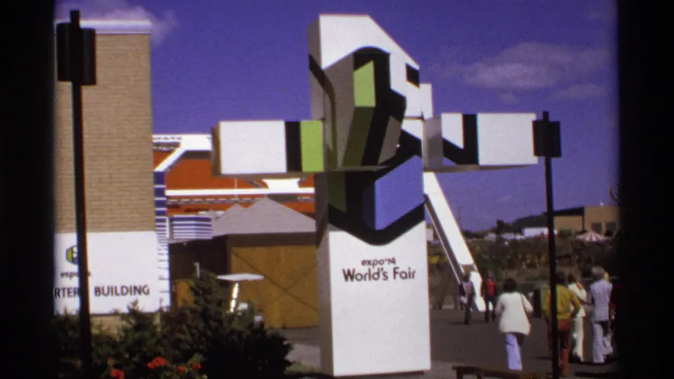 1970s fairground view of the Expo '74 World's Fair sculpture, with visitors walking past and the Art Center Building partly visible.