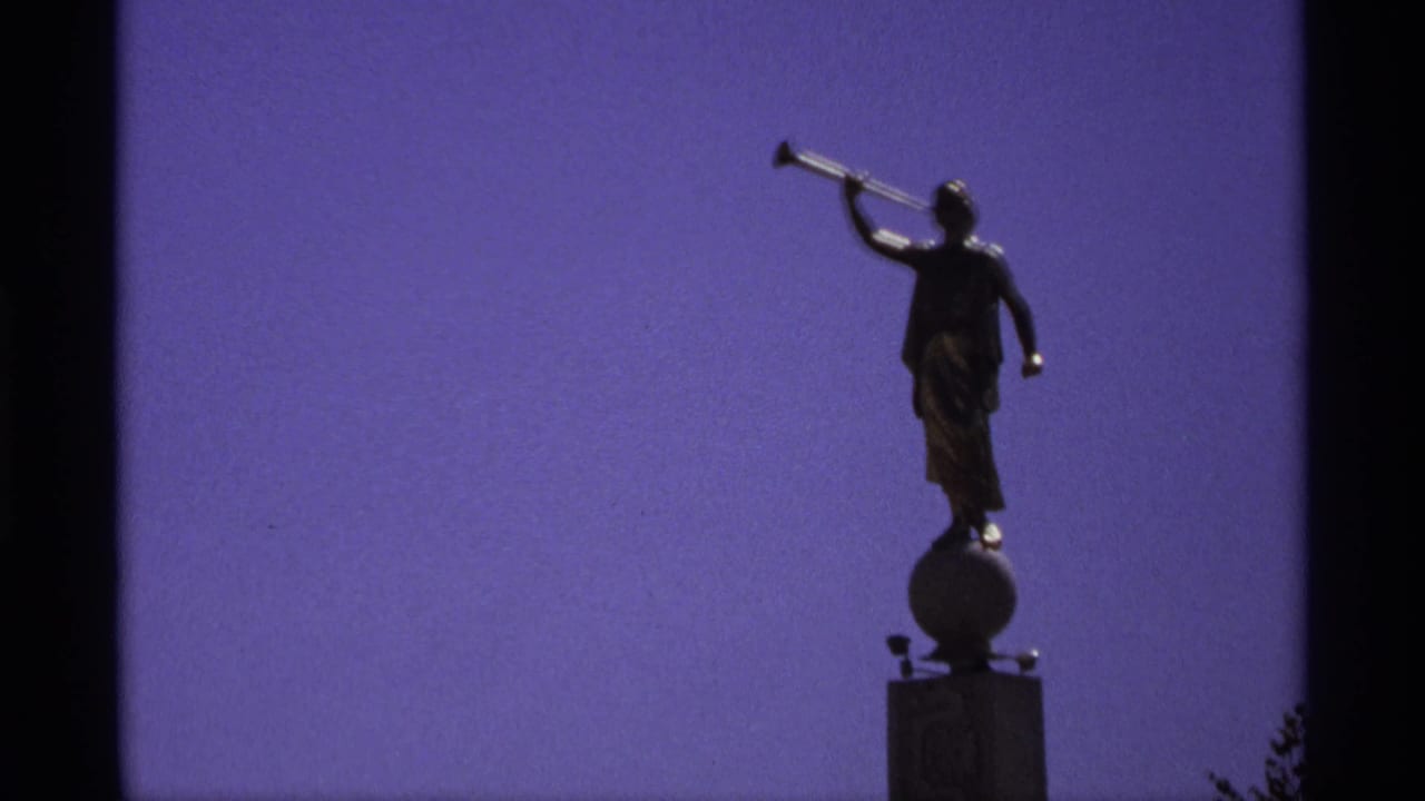 Silhouetted statue holding a horn against a purple sky.