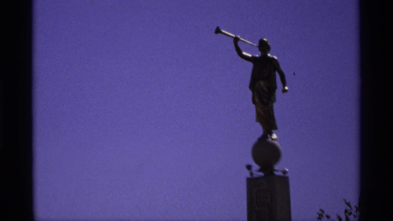 Statue with raised horn silhouetted against open sky.
