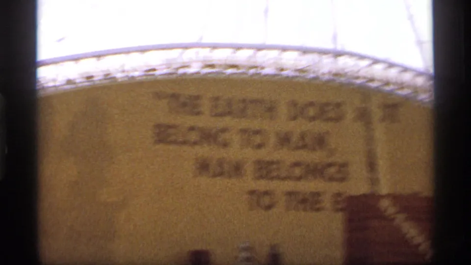 Soft 8mm frame showing the continuation of an environmental quote on a curved or broad exhibit wall.