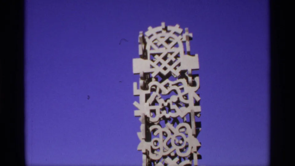 Close view of an ornate white geometric architectural structure filmed against a saturated blue sky on 8mm footage.
