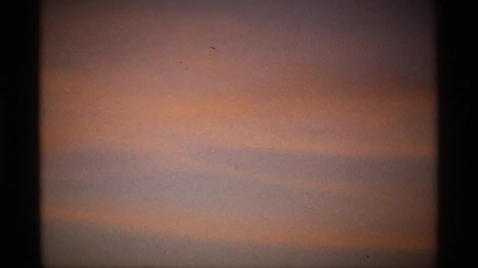 A hazy orange-gray sky frame on 8mm film, likely a brief transition away from the garden scene.