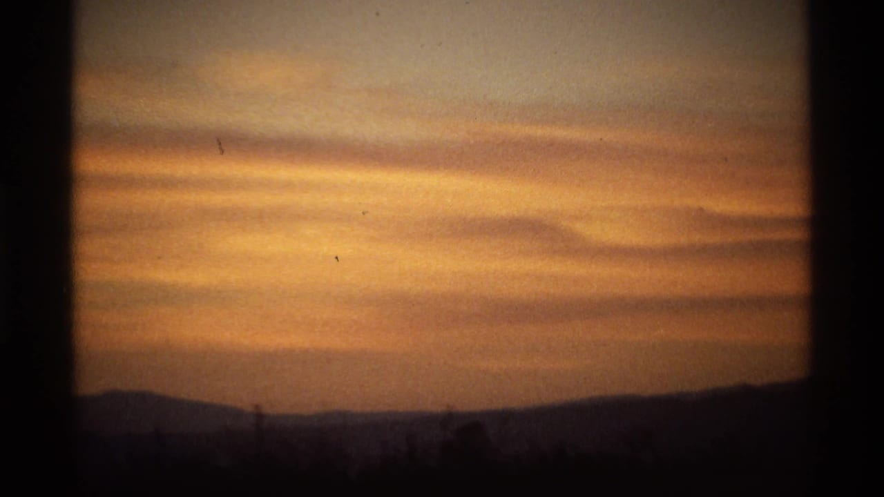 Orange sunset clouds above a dark distant hill line.