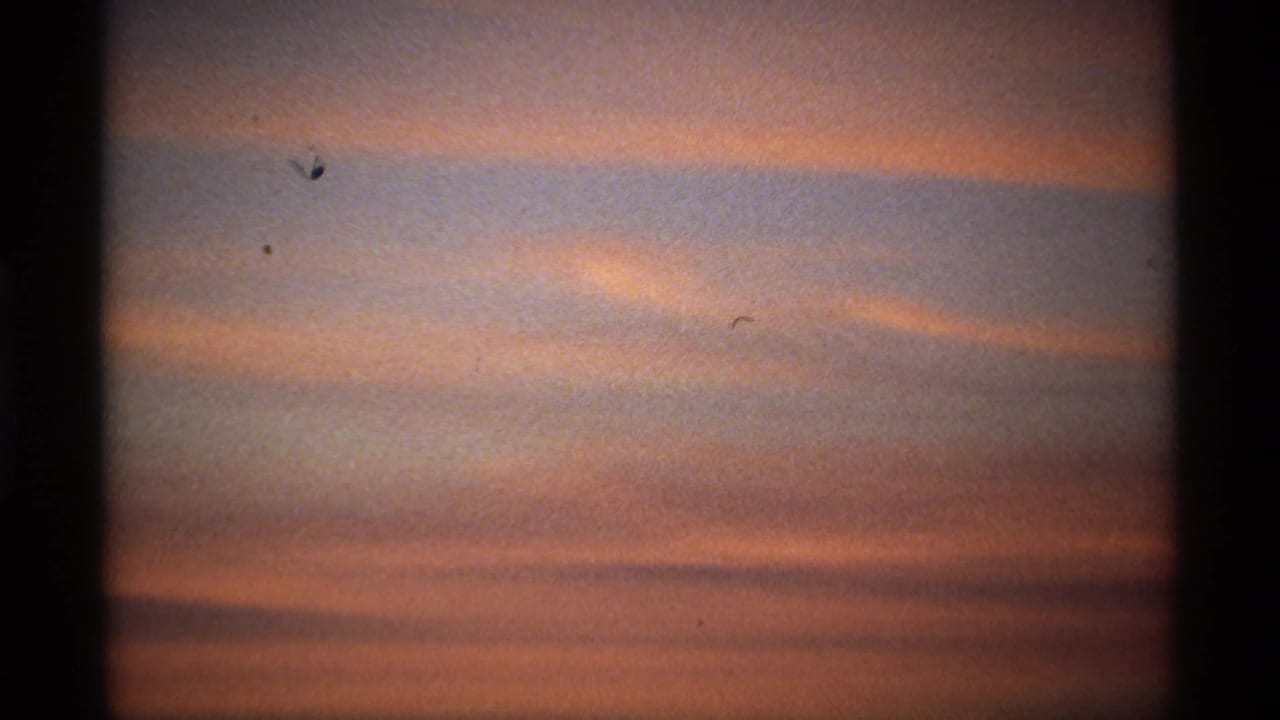 Pink and orange cloud bands fill the dawn sky within dark 8mm frame edges.