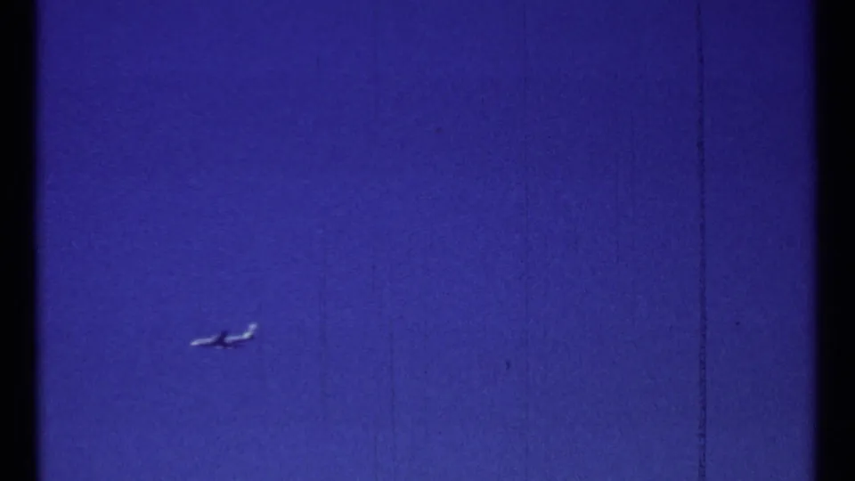 Small airplane crossing a cloudless blue sky in 1967 Montreal home-movie footage.