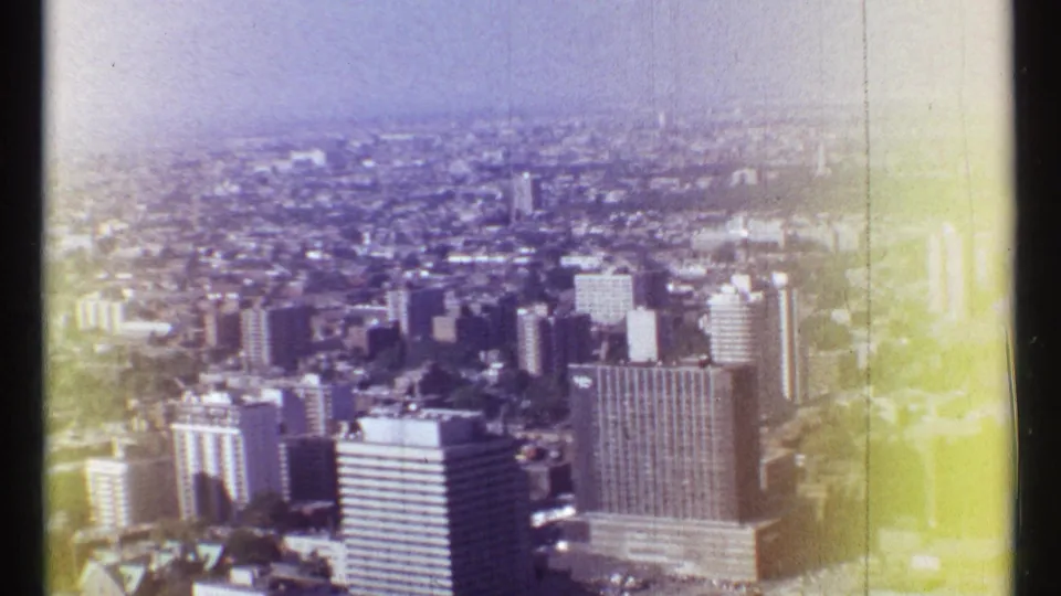 Aerial view over Montreal with mid-century high-rises and dense city blocks on faded 8mm film.