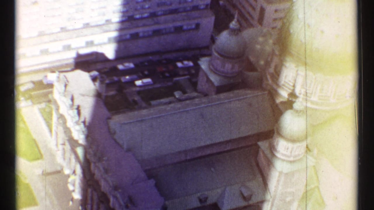 1967 Montreal home-movie frame showing a high-angle view of green domes and stone church architecture among downtown buildings.