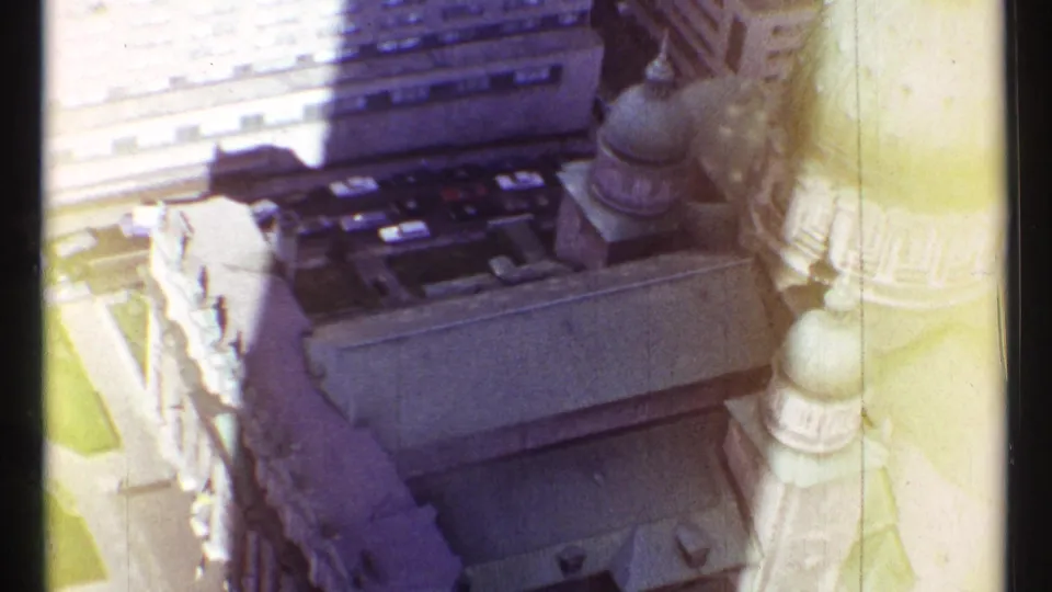 1967 Montreal home-movie frame showing a high-angle view of green domes and stone church architecture among downtown buildings.