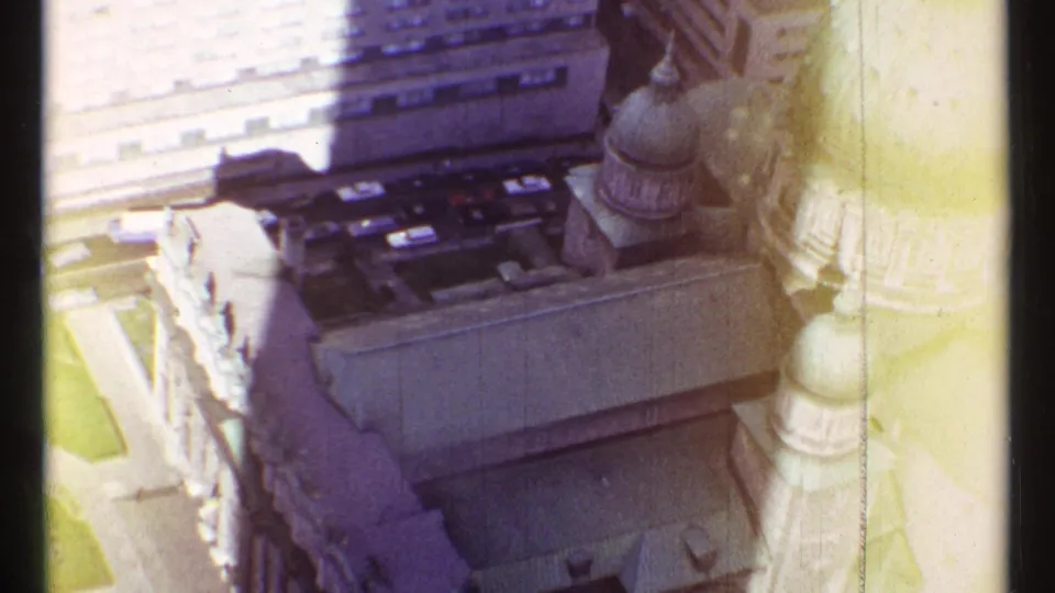 High-angle 1967 Montreal frame with church domes, pale stone detailing, rooftops, and nearby downtown structures.