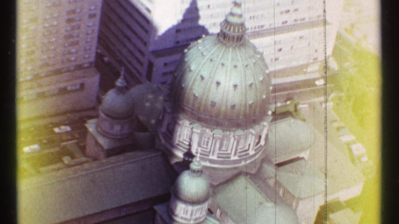 1967 Montreal aerial home-movie frame showing a green copper-domed cathedral among downtown high-rises.