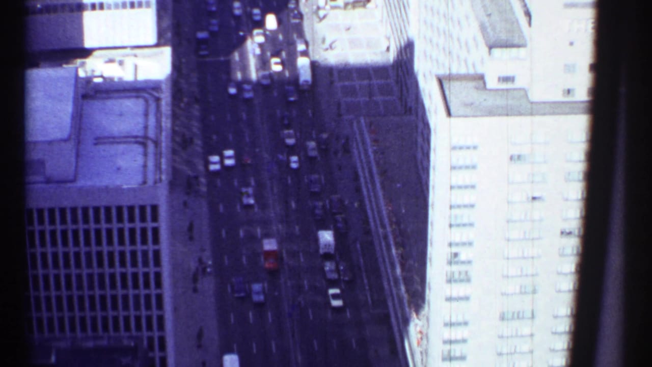 Aerial view of city street traffic between tall buildings.