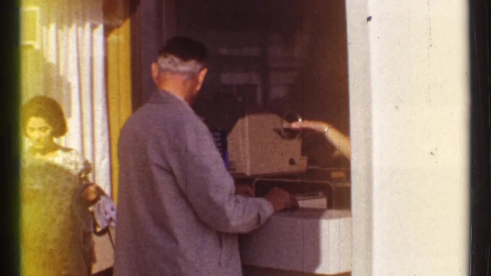 A booth attendant's arm reaches toward the suited visitor during a 1967 Montreal admission exchange.