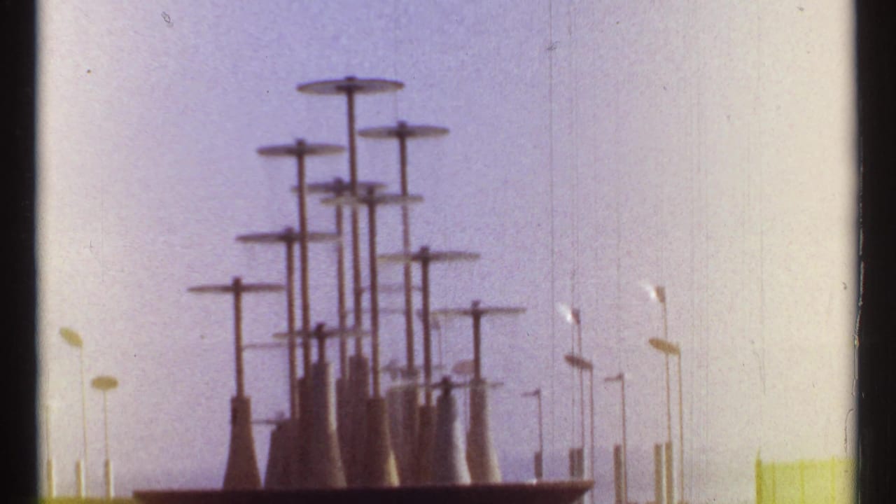 Cluster of tall capped towers against a pale hazy sky with film edge marks.