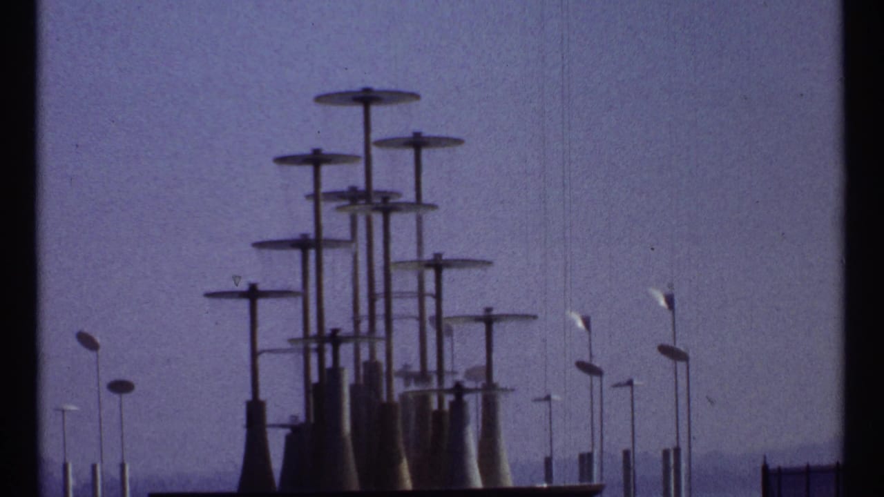Dark cluster of capped towers and streetlamps under a blue-purple sky.