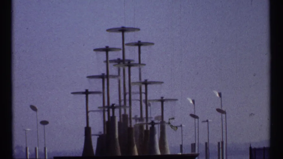 1967 Montreal 8mm still showing capped towers, streetlamps, and a low foreground edge in soft focus.