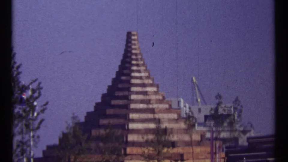 1967 Montreal frame showing a stepped brick tower-like structure, trees, and nearby industrial or fairground elements.