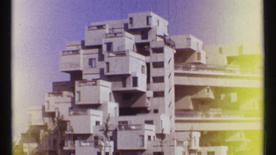 8mm frame of Habitat 67 in Montreal, with stacked concrete modules, balconies, and a bright light leak along the right edge.