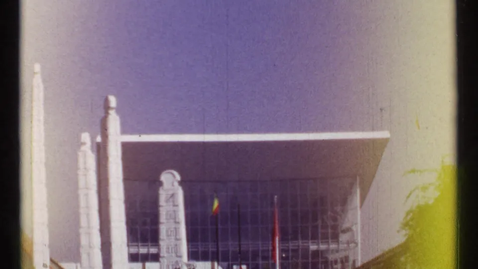 1967 Montreal 8mm frame showing the modernist facade, tall white pillars, flags, and strong film wash across the scene.
