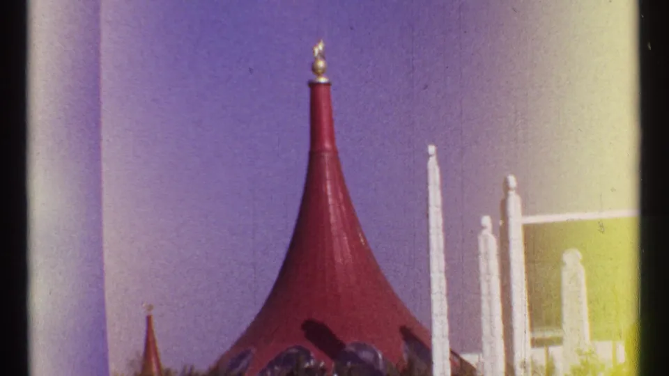 1967 Montreal 8mm frame showing a red conical pavilion-like roof with a gold finial and white vertical pillars against a shifted blue-purple sky.