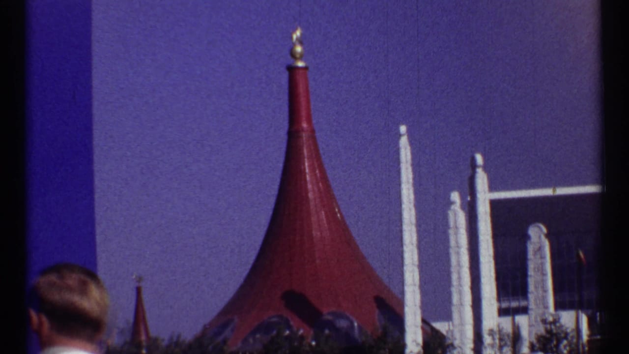 Red pointed roof, white pillars, and the back of a person's head in the foreground.