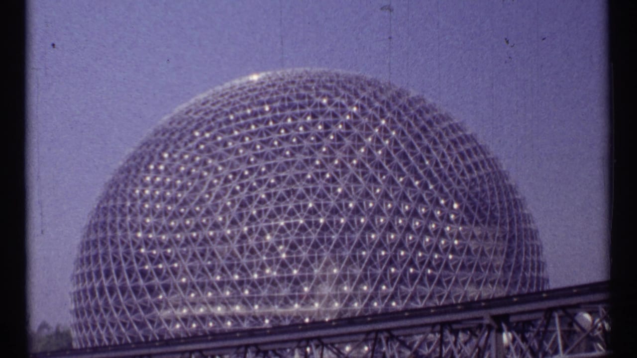 Geodesic dome behind an elevated rail track on faded 8mm film.
