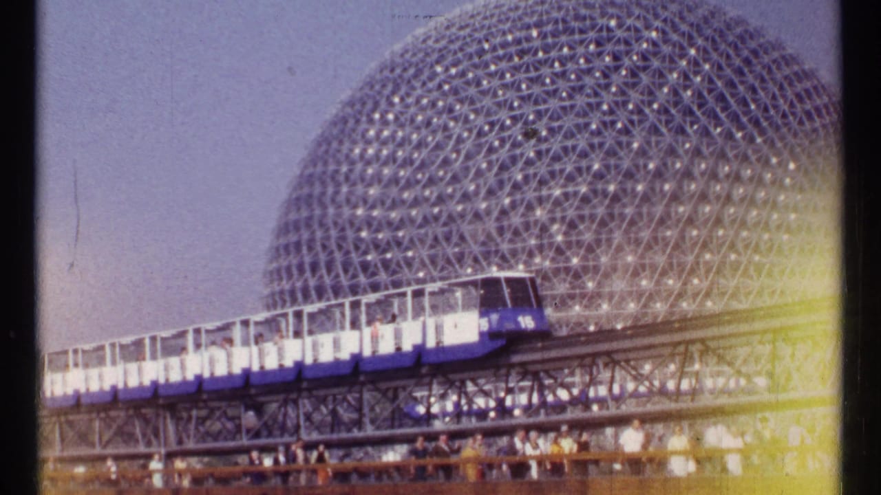 Blue and white monorail train passing in front of a geodesic dome.