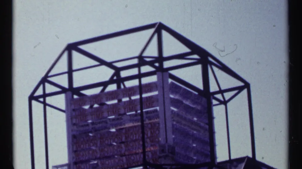 Expo 67 fairground structure with angular metal framing and a gridded display panel, seen in faded 8mm footage.
