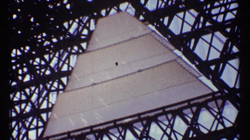 Closer 1967 Montreal frame of pale monument panels intersected by dark steel lattice and sky gaps.