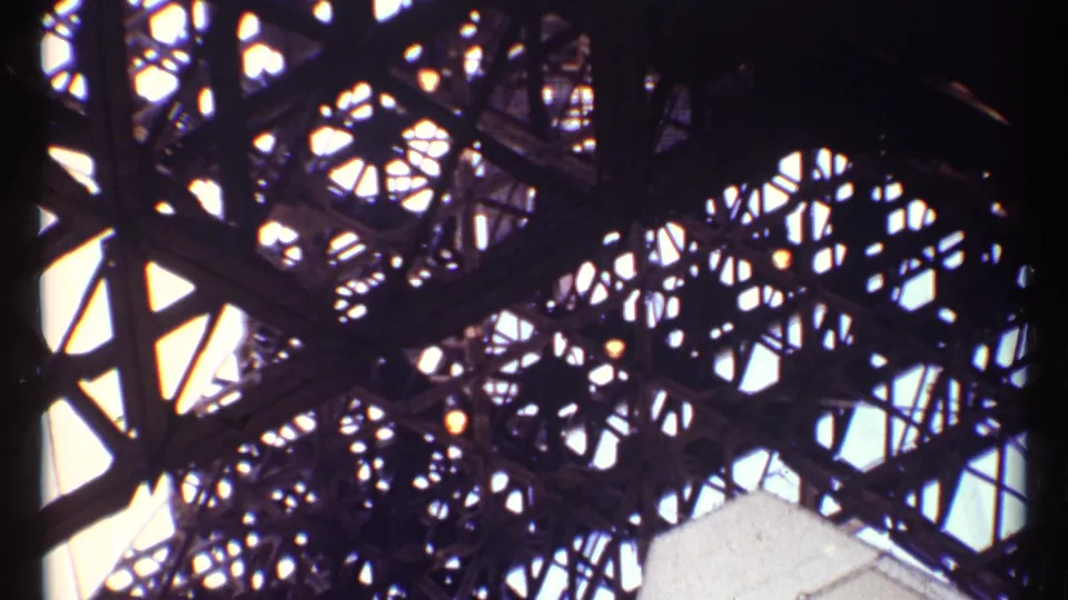 Low-angle 1967 Montreal view of overlapping steel trusses and geometric openings silhouetted against daylight.