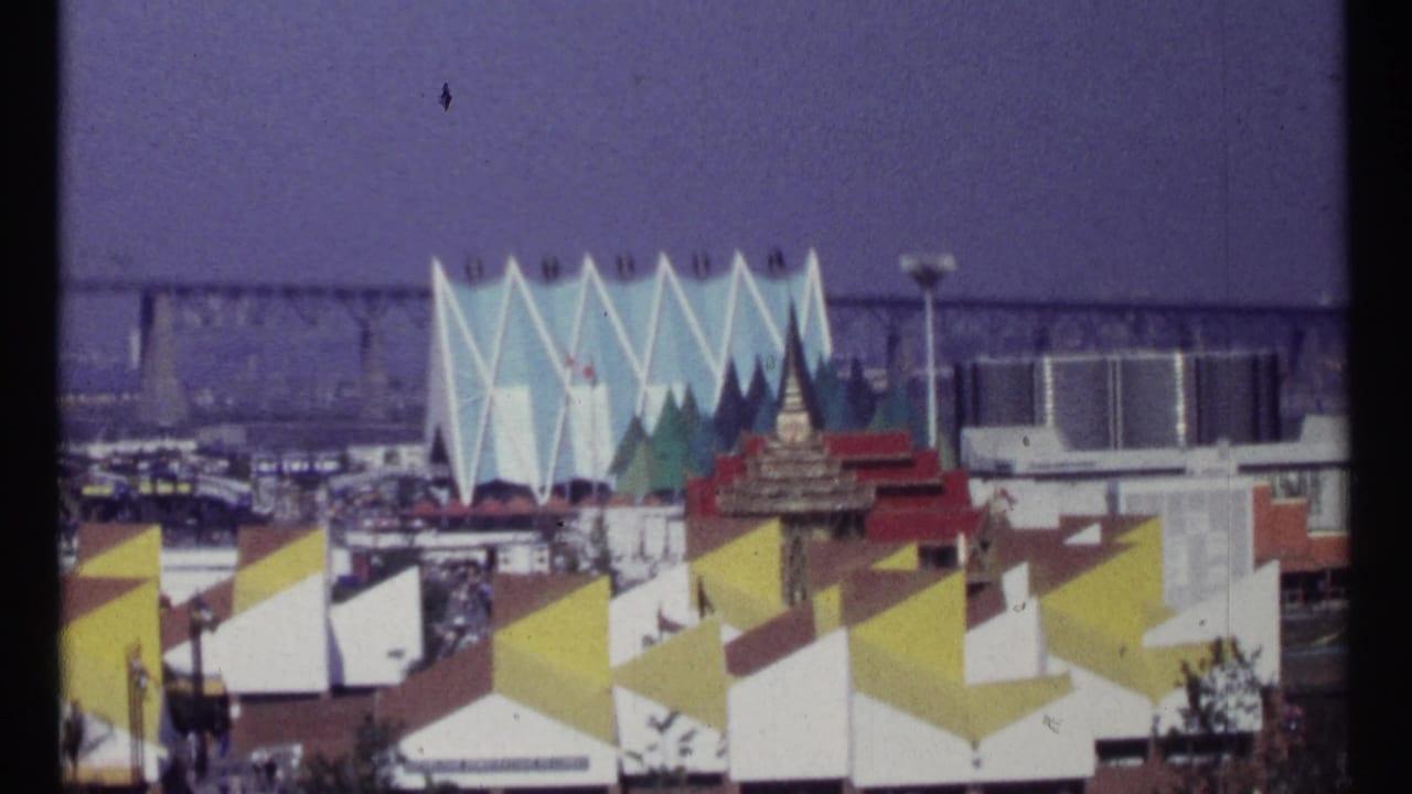 Angular fairground pavilions with blue jagged facade, flags, and yellow roof forms.