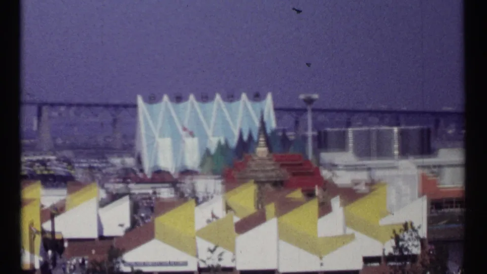 1967 Montreal Expo 67 pavilions with yellow and white roof geometry, flags, a blue jagged facade, and distant fair buildings.