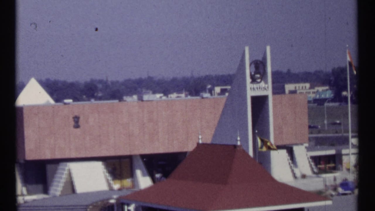 Similar wide view of the building, tower, flags, stairs, and red canopy roof.