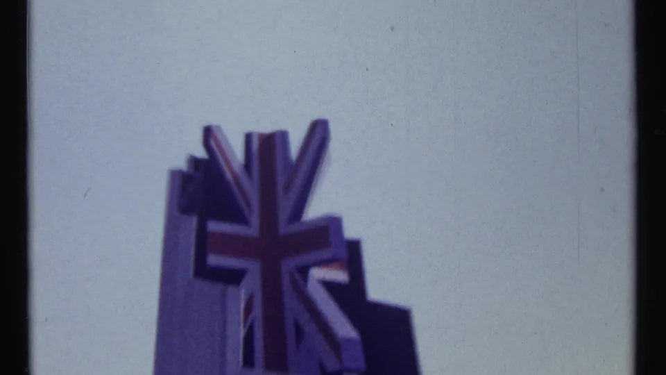 Close 1967 Montreal home-movie view of a Union Jack-style graphic emblem on a sculptural structure against the sky.
