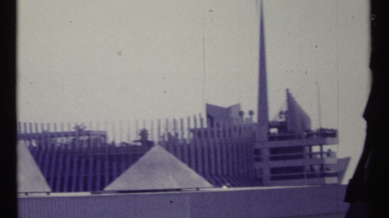 Modernist roofline with spire, ribbed wall, and geometric roof shapes.